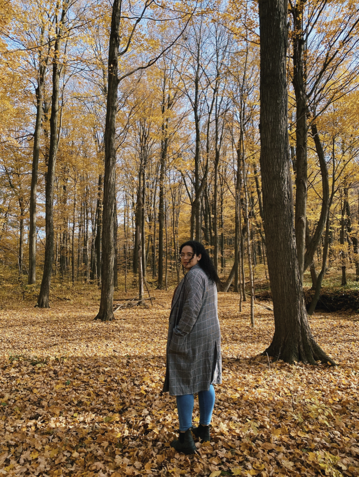 Photo of Melissa standing in a forest looking back at the camera